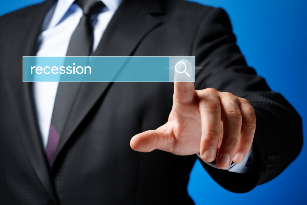 Photo of a Man in business attire and pointing at a search bar with the word "recession"